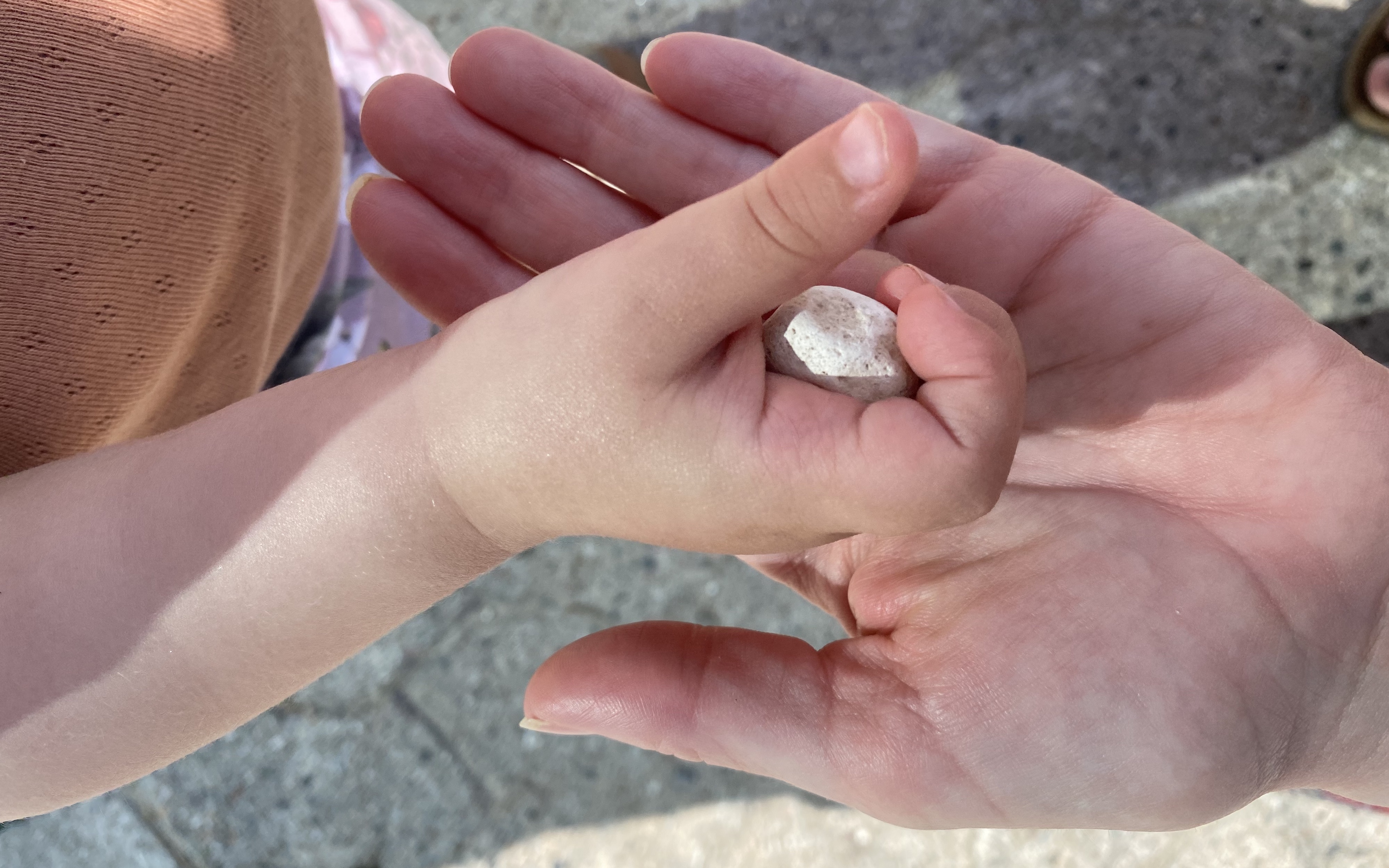Barnehånd giver sten til voksenhånd